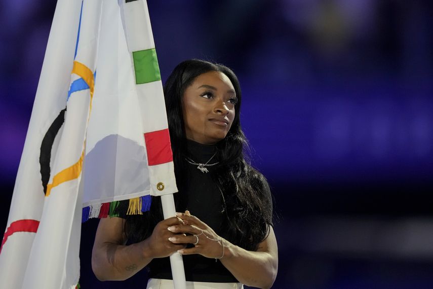 La gimnasta estadounidense Simone Biles sostiene la bandera olímpica durante la ceremonia de clausura de los Juegos Olímpicos de verano de 2024 en el Stade de France, el domingo 11 de agosto, en Saint-Denis, Francia.