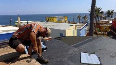 Un hombre trabaja en el sellado del techo de una casa afectada por el paso del huracán María en Puerto Rico.