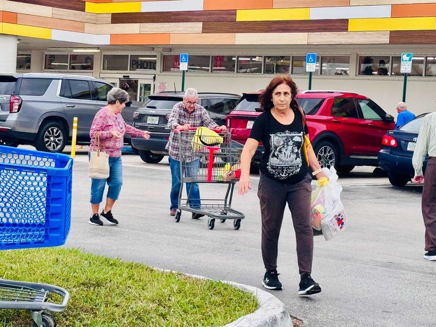 Personas saliendo del mercado, con el área de parqueo al fondo