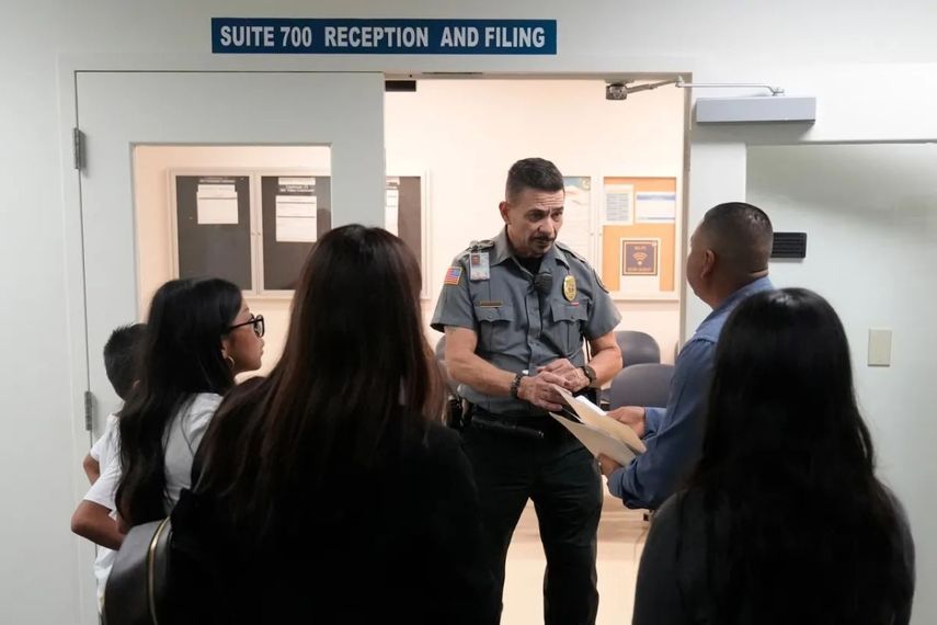 Un oficial escucha una pregunta mientras dirige a la gente a una sala del tribunal, el miércoles 10 de enero de 2024, en un corte de inmigración en Miami.