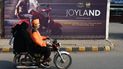 Una pareja pasa junto a una pancarta promocional de la película Joyland, producida en Pakistán, que se exhibe frente a un cine en Lahore el 16 de noviembre de 2022.