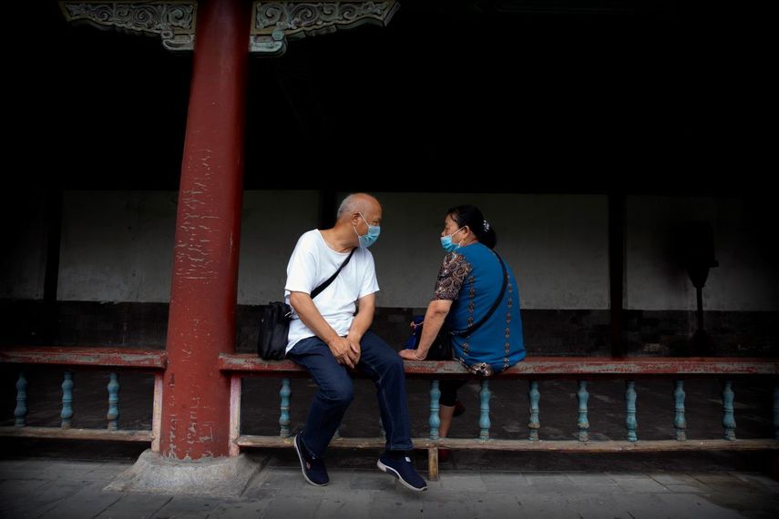 Un par de personas conversan portando cubrebocas en el Templo del Cielo, en Beijing, el sábado 18 de julio de 2020.