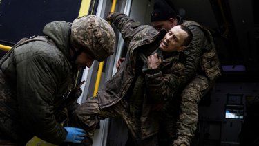 Médicos militares ucranianos ayudan a su camarada herido a salir de una ambulancia después de llegar del campo de batalla a un hospital de campaña cerca de Bájmut, Ucrania, el 26 de febrero de 2023.&nbsp;