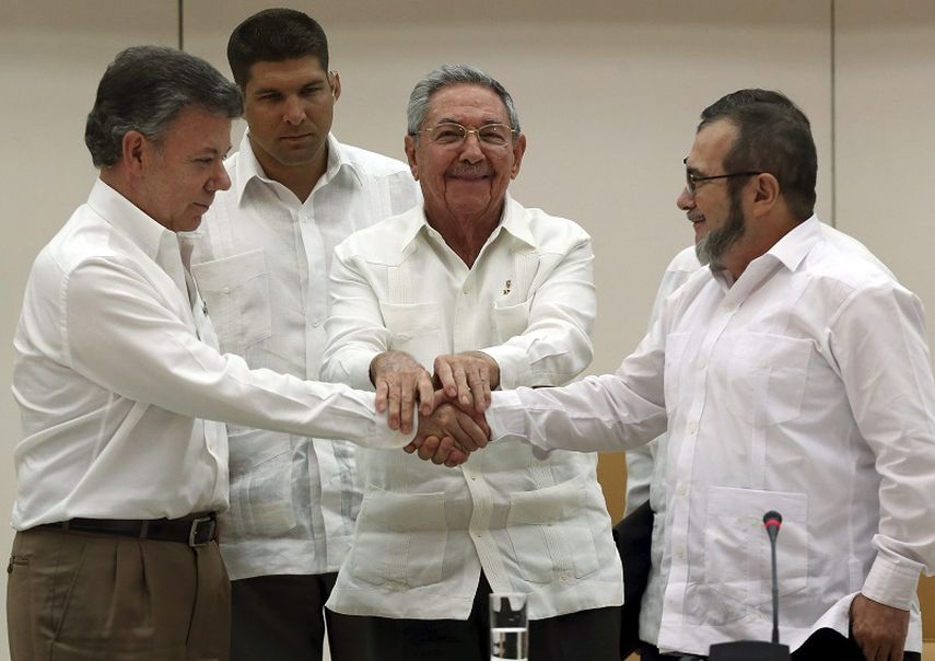 El presidente de Colombia Juan Manuel Santos (i), el de Cuba Raúl Castro (2-d) y el máximo líder de las FARC, Rodrigo Londoño (d), alias Timochenko, se dan la mano tras anunciar en La Habana el acuerdo alcanzado entre las partes en materia de justici