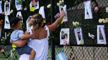 Victoria Mayer y su hijo Antonio visitan un memorial improvisado en el sitio de un edificio derrumbado en Surfside, Florida, al norte de Miami Beach, el 26 de junio de 2021. Victoria dijo que ha vivido en Surfside durante dos años y es originaria de Argentina. Un ingeniero advirtió sobre daños estructurales importantes en un edificio de apartamentos de Florida tres años antes de que colapsara parcialmente, según un informe el 26 de junio, mientras los rescatistas se apresuraban a encontrar a 159 personas aún desaparecidas en la montaña de restos. Se ha confirmado la muerte de cuatro personas después de que el edificio de 12 pisos frente al mar en Surfside colapsara cuando los residentes dormían adentro en las primeras horas del 24 de junio.