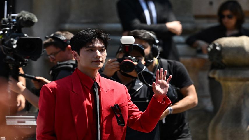 El actor chino Yang Yang saluda cuando llega para asistir al desfile de modas masculinas Primavera-Verano 2023 de Valentino el 16 de junio de 2023 como parte de la Semana de la Moda de Milán.