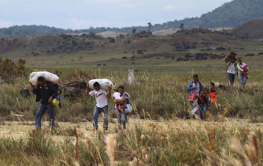 Un grupo de&nbsp;venezolanos camina hacia Brasil a través de un campo, en Pacaraima, estado de Roraima, Brasil, el viernes 22 de febrero de 2019.