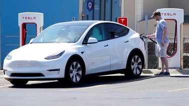 El conductor de un auto de Tesla recarga las baterías de su auto.