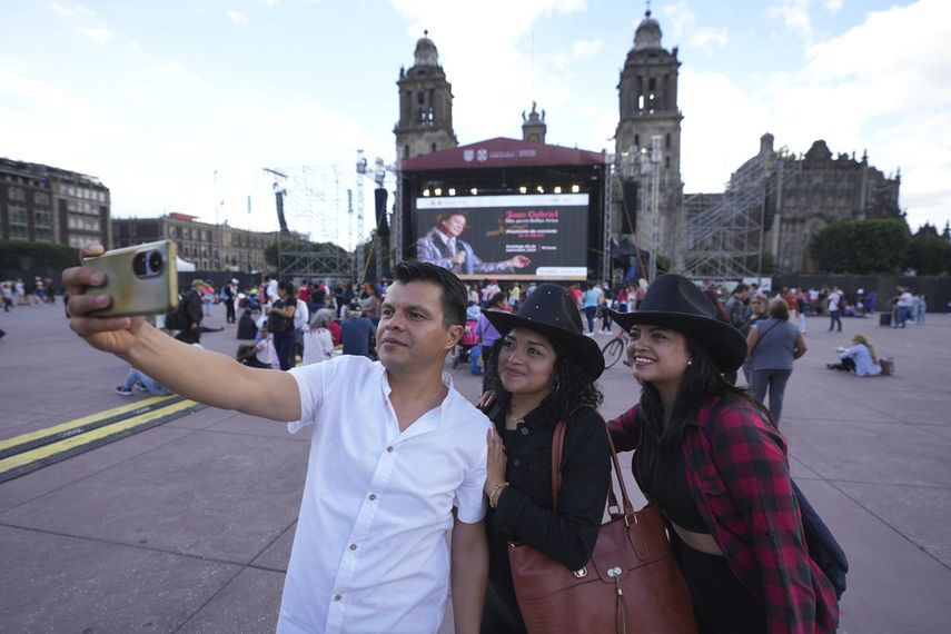 Manuel Torres se toma una selfie con su esposa Ana Ordaz, centro, y su hija Paola Torres previo a una proyección de un concierto de Juan Gabriel en el Zócalo, la plaza principal de la Ciudad de México, el domingo 22 de septiembre de 2024. 