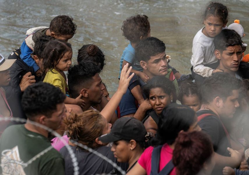 Migrantes cargan niños pequeños esperan en un barco de la Patrulla Fronteriza de Estados Unidos que los llevará a un área de procesamiento, luego de horas de espera bajo el sol a lo largo del Río Grande, en Eagle Pass, Texas, el 25 de septiembre de 2023.