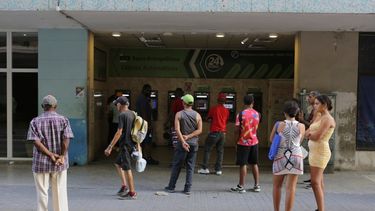 Varias personas esperan en el exterior de un banco para poder retirar pesos cubanos de un cajero automático, en La Habana.