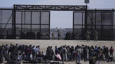 Migrantes que cruzaron la frontera desde México hacia Estados Unidos esperan a un costado del muro fronterizo en donde agentes de la Patrulla Fronteriza de Estados Unidos montan guardia, el 30 de marzo de 2023, en una imagen tomada desde Cuidad Juárez, México.&nbsp;
