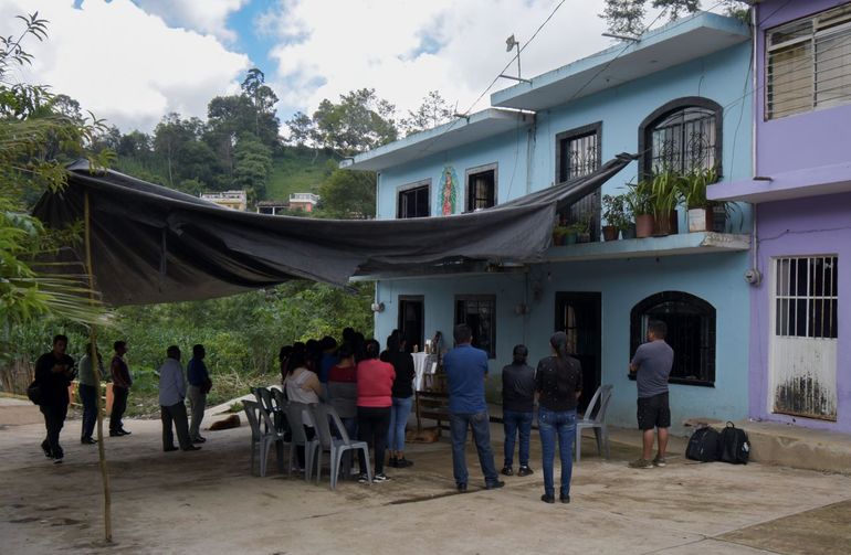 Un toldo protege del sol a vecinos, familiares y amigos que ofrecen consuelo a las familias de los hermanos Yovani y Jair Valencia Olivares y de su primo Misael Olivares en San Marcos Atexquilapan (México) el 30 de junio del 2022.
