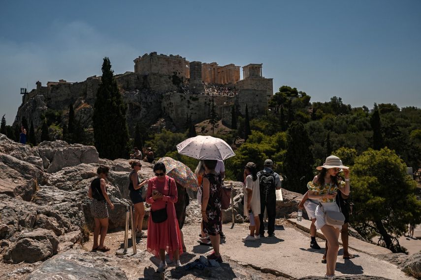 Turistas, algunos con paraguas, se reúnen frente a la Acrópolis de Atenas el 8 de julio de 2025.