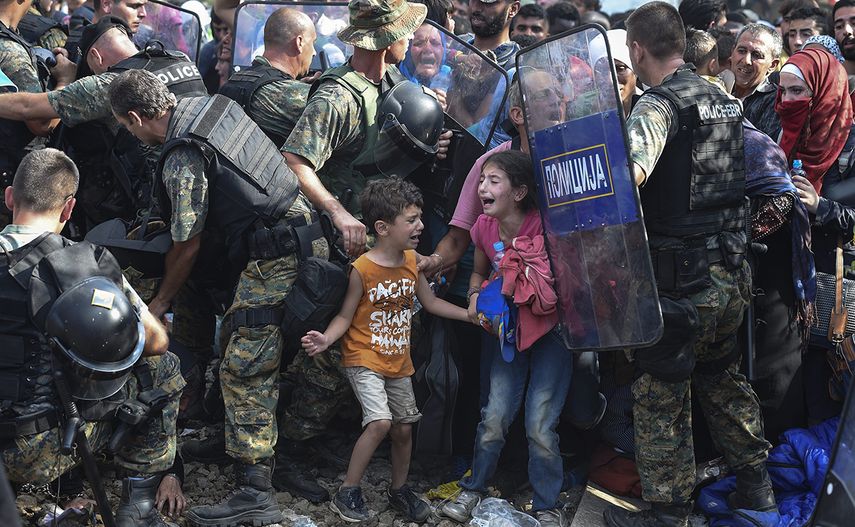 Fotografía tomada por Georgi Licovski que muestra a dos niños migrantes que lloran mientras otros refugiados intentan romper el cordón policial para cruzar a la Macedonia procedentes de Grecia. La instantánea recibió el premio Unicef a la Foto del año