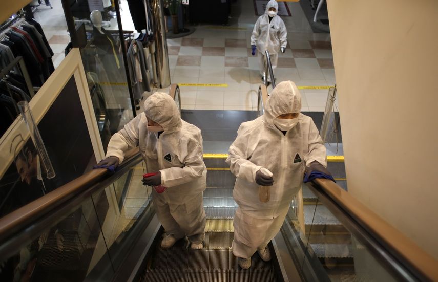 Trabajadores con equipo de protección rocían desinfectante como protección contra el nuevo coronavirus en unos grandes almacenes de Seúl, Corea del Sur, el lunes 2 de marzo de 2020.