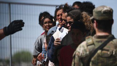 Migrantes hacen cola para en la frontera para solicitar asilo en Estados Unidos.