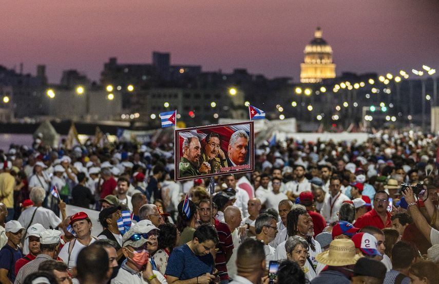 Personas sostienen fotografías del designado gobernante cubano Miguel Díaz-Canel, el dictador cubano Raúl Castro y el difunto Fidel Castro durante una celebración del Día del Trabajador en La Habana, Cuba, el viernes 5 de mayo de 2023. 