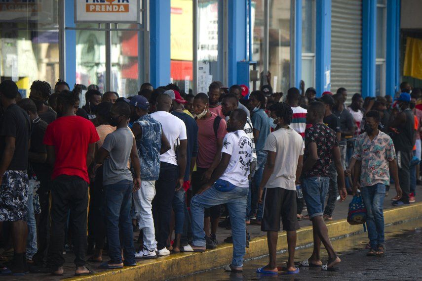 Migrantes haitianos y centroamericanos esperan que los bancos de remesas abran para retirar el dinero enviado por sus familiares en Tapachula, estado de Chiapas, México.&nbsp;