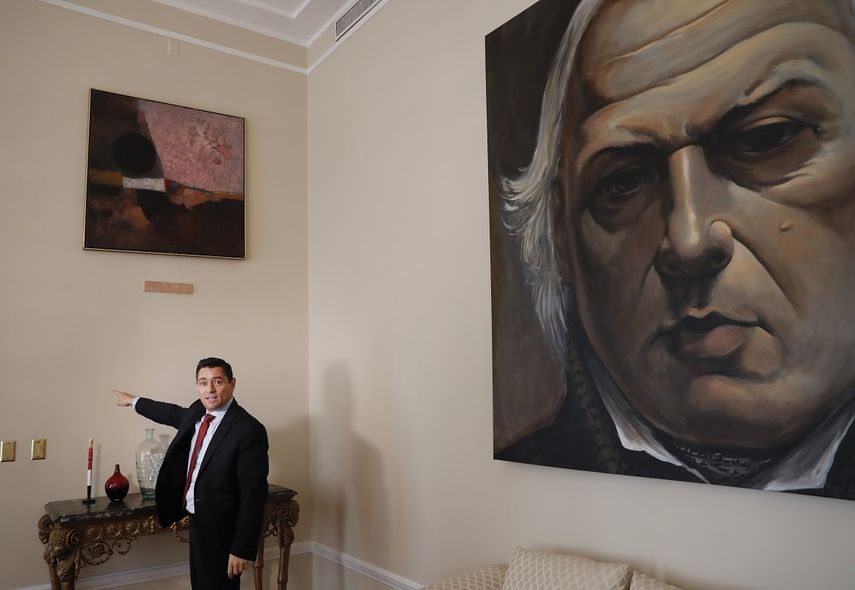 En esta foto del 17 de septiembre de 2019, Carlos Vecchio,&nbsp;embajador de Venezuela en Estados Unidos, se&ntilde;ala una secci&oacute;n vac&iacute;a de una pared donde una vez colg&oacute; una obra de arte en la residencia del embajador en Washington.&nbsp;