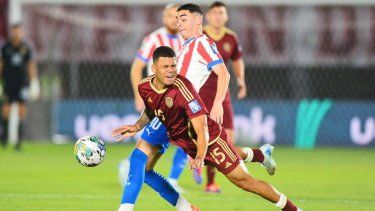 El defensor venezolano Miguel Navarro pelea por despejar el balón frente al atacante paraguayo Miguel Almirón, el 15 de octubre de 2024.