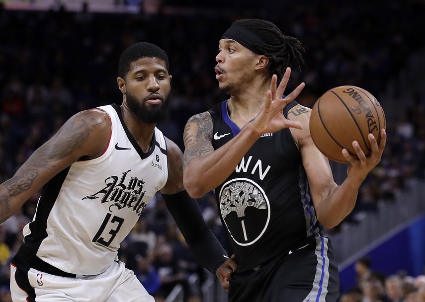 En foto de archivo dle 10 de marzod el 2020 Damon Lee de los warriors mientras lo defiende Paul George de los Clippers de Los &Aacute;ngeles. El 9 de abril del 2020, el entrenador de los Clippers Doc Rivers dijo que los jugadores se est&aacute;n entrenando con videoconferencias en las que 10 jugadores participan en ejercicios con el equipo de rendimiento.