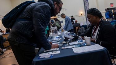 Un hombre busca opciones en una feria de empleo.