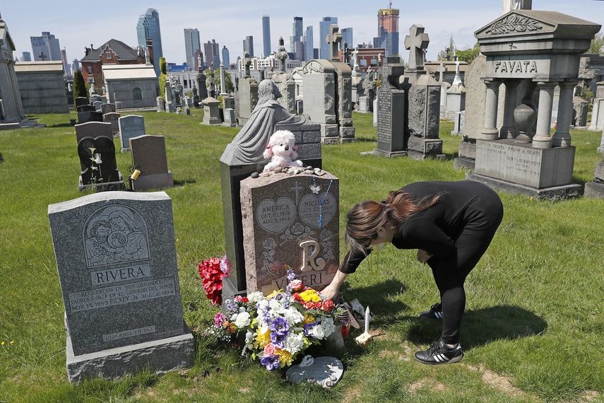 Una mujer coloca flores en una tumba en el cementerio Calvary, en Nueva York.