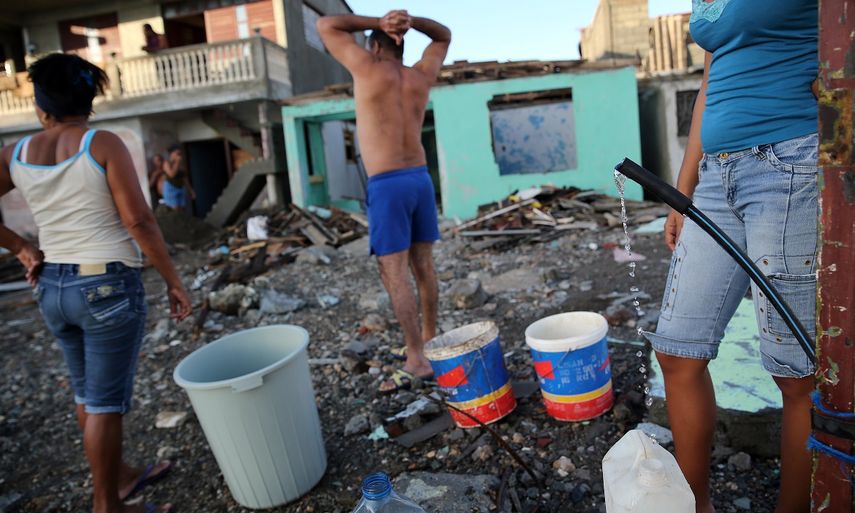 Residentes de Baracoa acopian agua sobre los escombros que dejó Mattew a su paso por el oriente cubano.