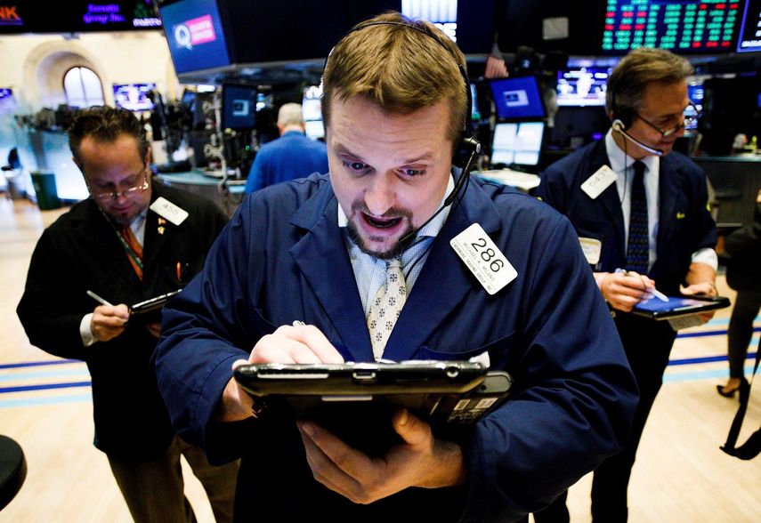 Varias personas trabajan en Wall Street, la Bolsa de Nueva York, Estados Unidos, que cerró este 12 de febrero con un fuerte impulso al alza.