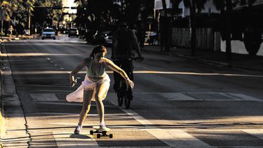 Una mujer rueda un patineta por las calles de Ocean Drive en, Miami Beach.