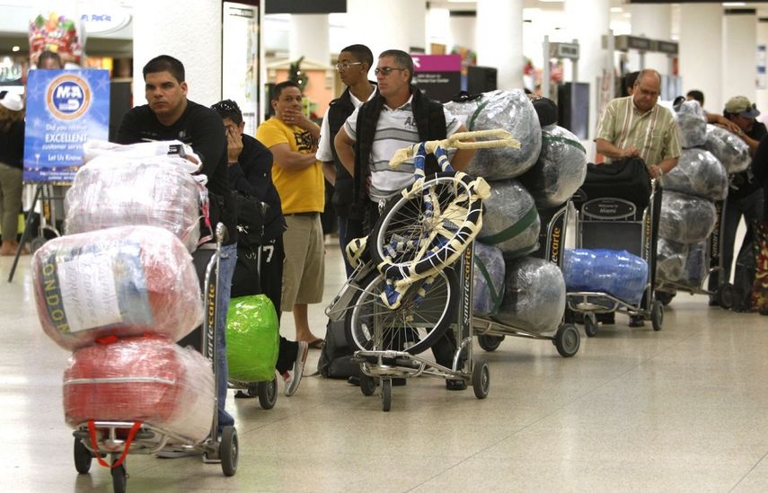 Varios viajeros esperan una fila con su equipaje en el aeropuerto internacional de Miami antes de viajar a Cuba. 