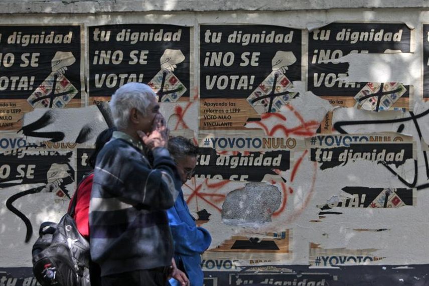 Unas personas caminan frente a afiches de campaña en un centro de votación previo a las elecciones generales que se realizarán este domingo en Guatemala. (EFE)