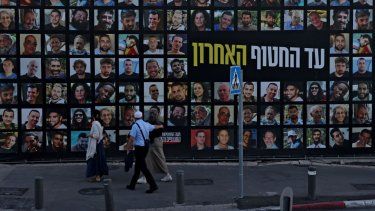 Personas observan una valla publicitaria que muestra los retratos de israelíes secuestrados por los terroristas de Hamás y que permanecen como rehenes en la Franja de Gaza desde octubre de 2023, en Jerusalén el 6 de octubre de 2025.