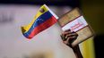 Una mujer sostiene una bandera venezolana y un libro sobre la disputa del territorio de Esequibo en Caracas, el miércoles 29 de noviembre de 2023.