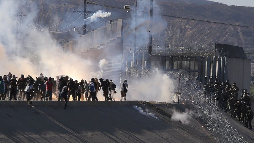 La policía fronteriza lanza gases lacrimógenos&nbsp;para evitar que grupos de inmigrantes crucen la garita El Chaparral, de la ciudad de Tijuana, rumbo a EEUU.