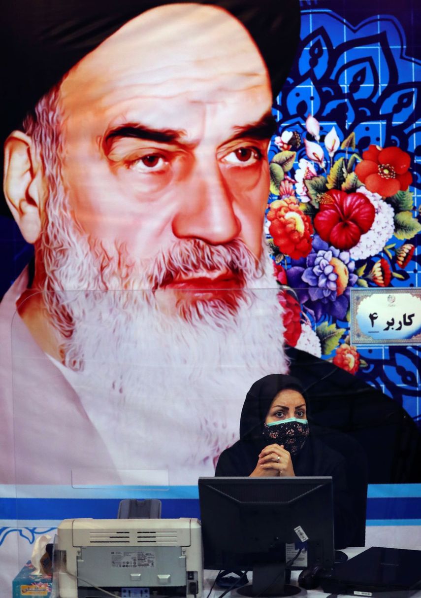 Bajo un retrato del difunto fundador de la República Islámica de Irán Ayatola Khomeini, una miembro del personal de la oficina de elecciones se apresta a registrar candidatos para le elección presidencial del 18 de junio, en Teherán, el martes, 11 de mayo del 2021.&nbsp;