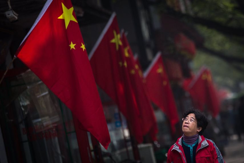 Una mujer pasa junto a una bandera&nbsp;china&nbsp;colgada en el barrio de Hutong durante la tercera jornada del el XIX Congreso del Partido Comunista de&nbsp;China&nbsp;(PCCh) en Pekín (China)el pasado 20 de octubre de 2017.&nbsp;