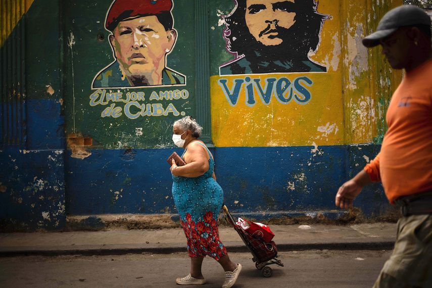 Una mujer&nbsp;con m&aacute;scarilla protectora&nbsp;contra el&nbsp;coronavirus tira de su carrito de compras mientras camina hacia el mercado en La Habana.&nbsp;