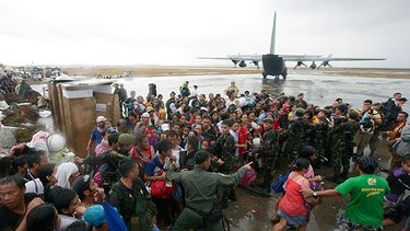 Sobrevivientes del tifón tratan de abordar un avión militar de transporte C-130 en la ciudad de Tacloban, provincia de Leyte, Filipinas. (Foto AP/Bullit Marquez)