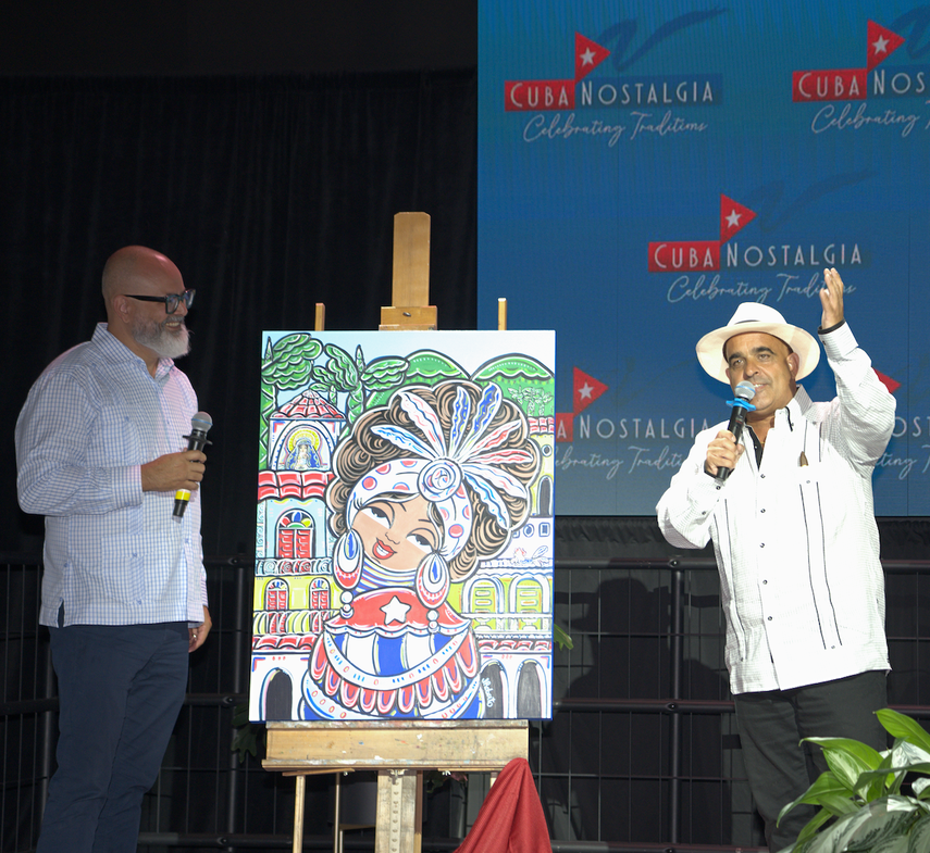El artista cubanoamericano Julio Roberto, junto a su obra Celia en su nostalgia, y Peter Regalado dirigiéndose a los medios.