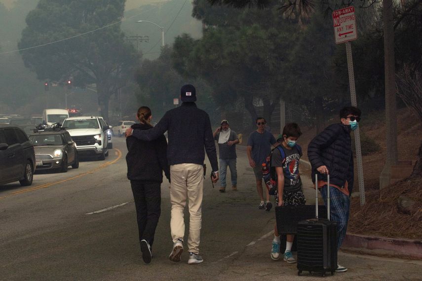 La gente evacua el área de Sunset Boulevard mientras el incendio Palisades arde en medio de una poderosa tormenta de viento el 7 de enero de 2025 en el vecindario Pacific Palisades de Los Ángeles, California.