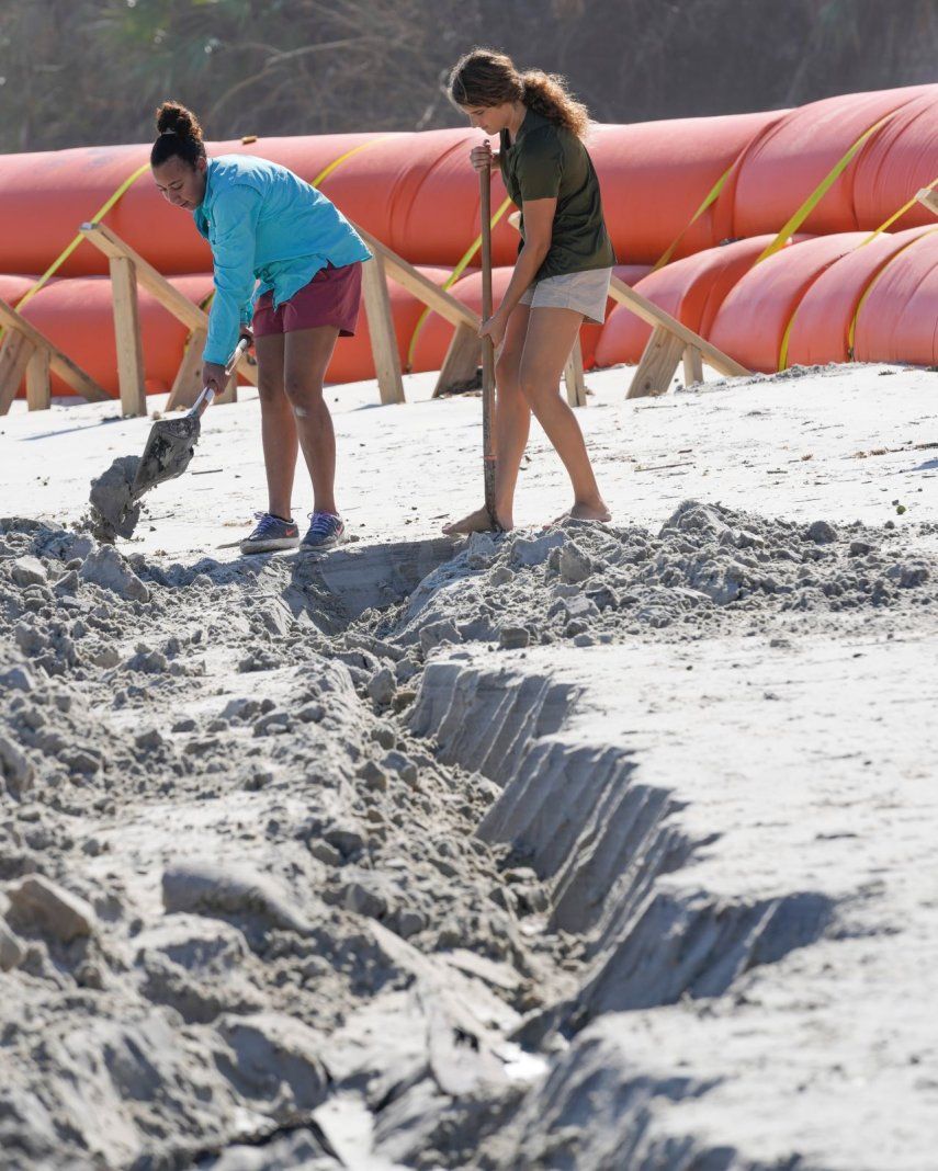 Las voluntarias Suzzanna Rogers, izquierda, y Olivia Storkamp, trabajan con arqueólogos para desenterrar una estructura expuesta de madera que se cree corresponde al naufragio de un barco de principios del siglo XIX en una playa, en Daytona Beach, Florida, el martes 6 de diciembre de 2022.&nbsp;