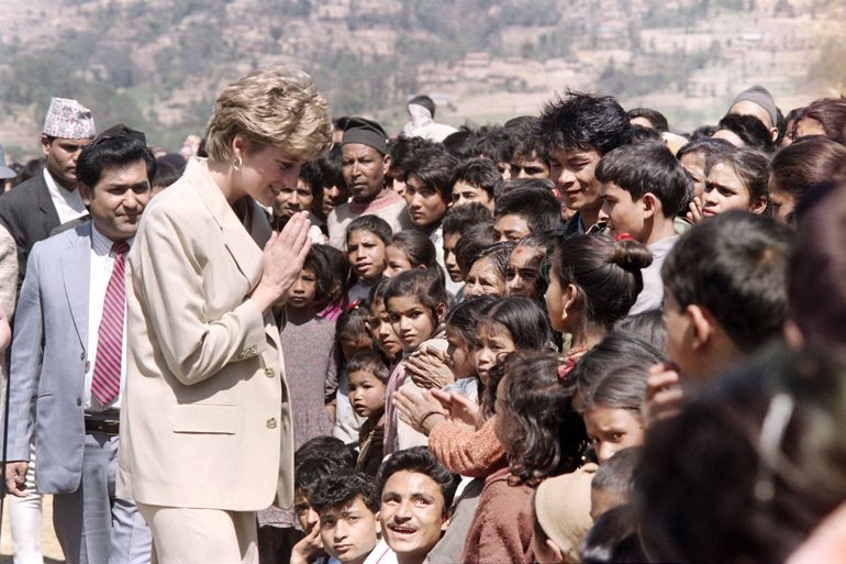En esta foto de archivo tomada el 5 de marzo de 1993, la princesa Diana une su mano mientras mira a los niños nepalíes cuando recorre las rústicas estribaciones del Himalaya, a través de un proyecto de la Cruz Roja.