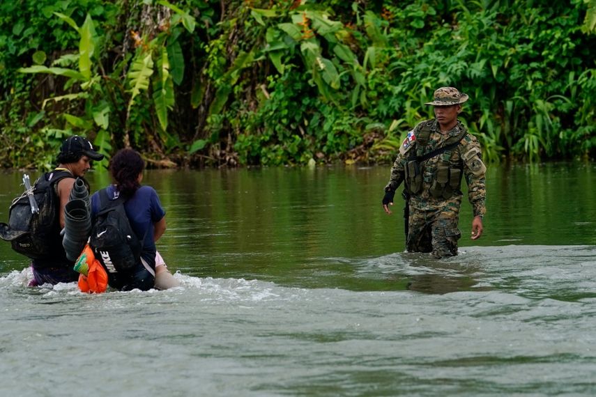Un agente fronterizo panameño observa mientras dos migrantes cruzan el río Tuquesa tras recorrer a pie el Tapón del Darién, en Bajo Chiquito, Panamá, el 4 de octubre de 2023.&nbsp;