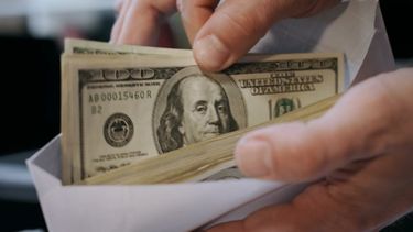 Persona con un sobre de billetes de 100 dólares&nbsp;