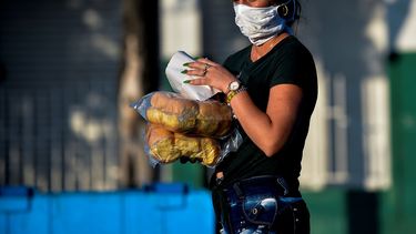 Una mujer con una mascarilla camina por una calle en La Habana con dos bolsas de pan el 17 de abril de 2020.
