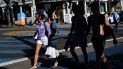 Una mujer cargas bolsas de compras mientras cruza una calle en Manhattan Beach, California.