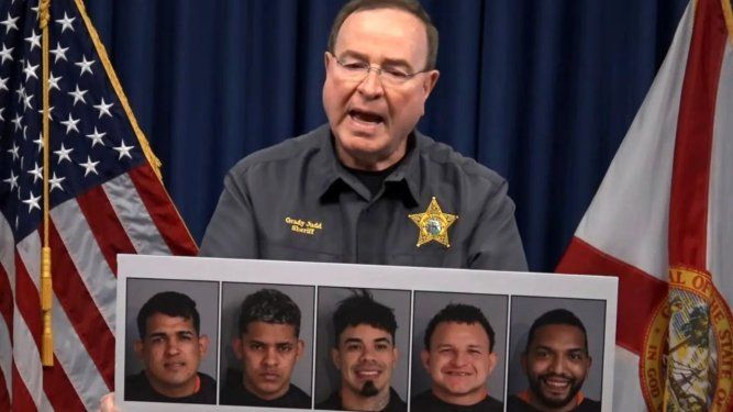 Grady Judd, sheriff del condado de Polk, sostiene un cartel con las fotografías de los cinco presuntos miembros del Tren de Aragua detenidos en Florida