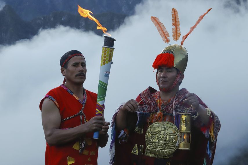 En esta foto distribuida por la Organización Deportiva Panamericana, dos hombres con atuendos incas participan en la ceremonia de llegada de la llama de los Juegos Panamericanos a Machu Picchu.